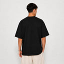 Vue arrière du t-shirt Tsitsit noir oversize uni Eliorness montrant la coupe ample et le tombé d'épaules bas.