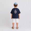 Vue arrière du t-shirt Tsitsit bleu marine enfant oversize Eliorness montrant la grande flamme blanche Aech Sheli brodée au dos et la kippa assortie.