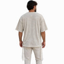 Vue de dos du t-shirt Tsitsit Effet Lin beige Eliorness porté, sur fond blanc, avec la petite flamme Aech Cheli brodée ton sur ton sous le col.