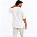 Vue de dos du t-shirt Tsitsit Effet Lin blanc Eliorness porté, avec la flamme Aech Cheli brodée blanc et contour bleu sous le col.