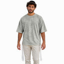Homme portant le t-shirt Tsitsit Effet Lin gris menthe Eliorness, vue de face sur fond blanc : coupe oversize, maille chinée, zips latéraux et tsitsit blancs aux quatre coins.